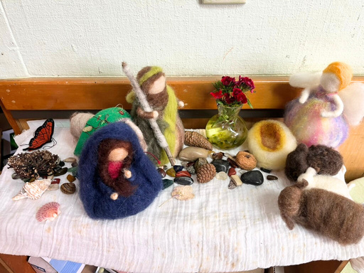 A simple Advent nature table with felted trees, a blue cloth, small dolls, and gathered natural items