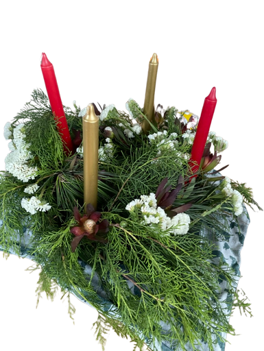 An Advent wreath of evergreens with four candles, two red and two gold, surrounded by berries