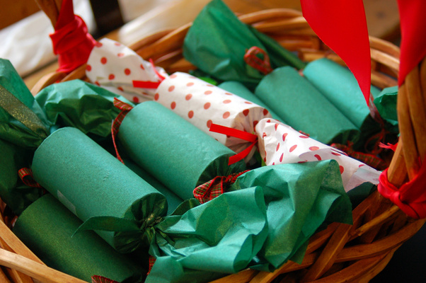 Handmade Christmas crackers in green and red patterned paper, tied with ribbon, in a basket