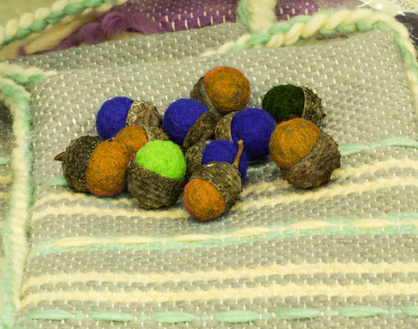 Small wet-felted wool acorns in blue, green, orange, and pink, topped with real acorn caps