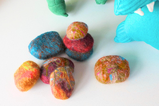 Wet-felted stones in marbled reds, blues, oranges, and golds on a table