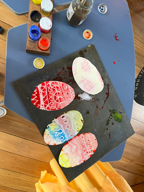Painted paper Easter eggs with wax-resist patterns in pink, red, and pastel colours