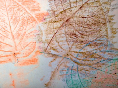 Close-up of autumn leaf rubbings in orange, green, and brown crayon on paper