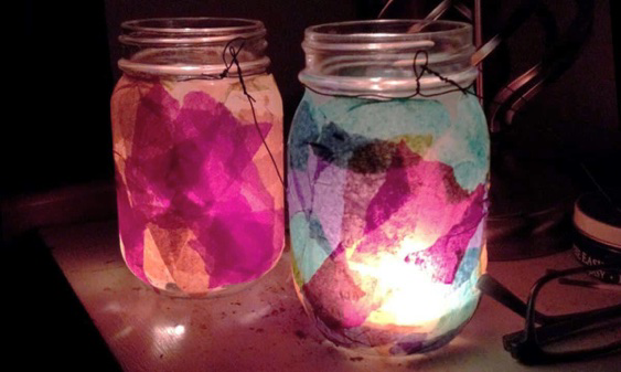 Two glass jar lanterns glowing pink and blue with tissue paper inside, lit by tea lights