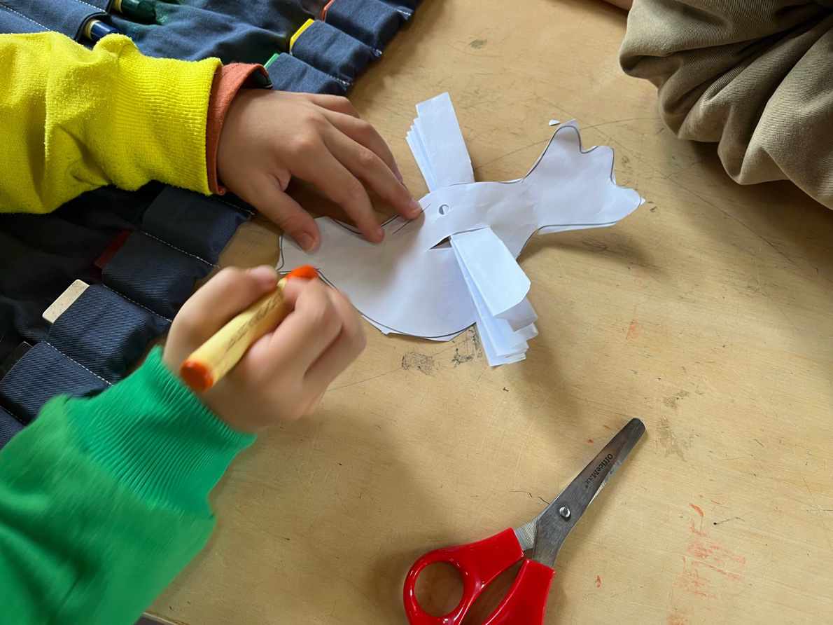 A child cutting a small white paper dove with scissors at a table